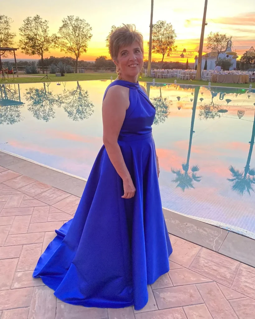 Mujer con traje de invitada junto a una piscina al atardecer